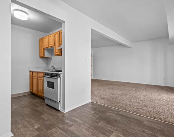 the kitchen and living room of an empty house with white walls and wood flooring