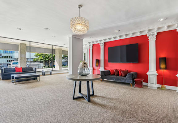 A living room with a grey carpet and a grey table with a vase on it.