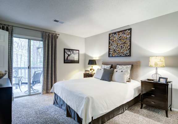 Apartments in Marietta Georgia for Rent – Wood Pointe Apartments - A bedroom with a large bed, a chair, and a painting on the wall.
