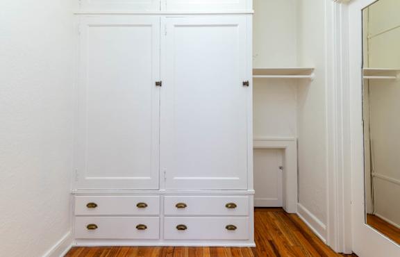A white wardrobe with four drawers is in a room.