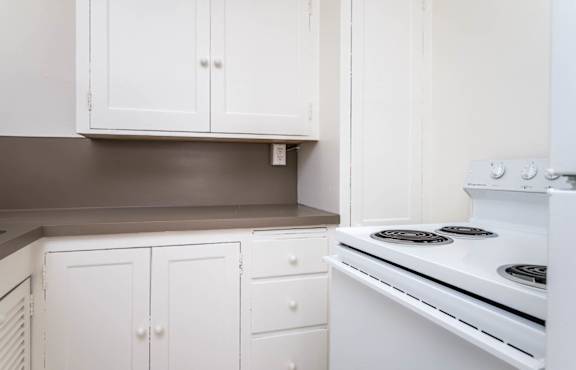 A white kitchen with a stove and cabinets.