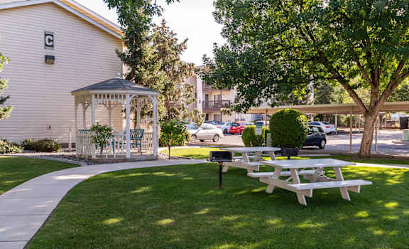 A gazebo sits in a grassy area next to a picnic table.