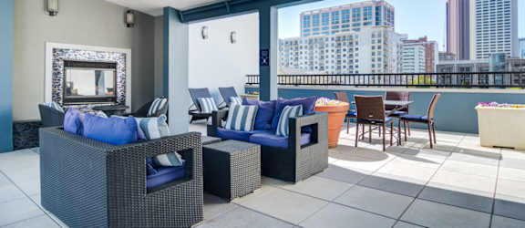 a seating area with couches and chairs and a fire place on a balcony with a city