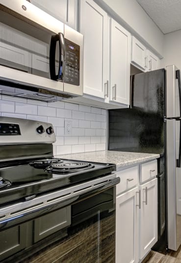 a kitchen with stainless steel appliances and white cabinets at The Edge of Germantown, Memphis, TN