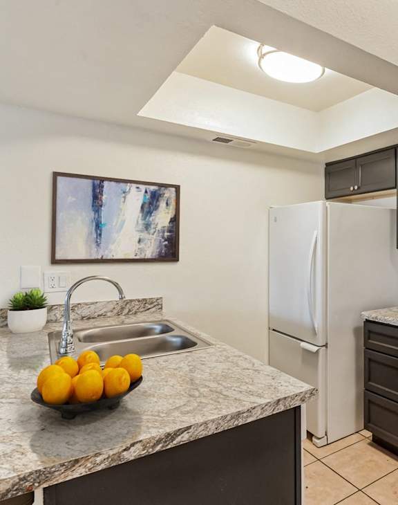 A kitchen with a white refrigerator, white oven, and black cabinets.