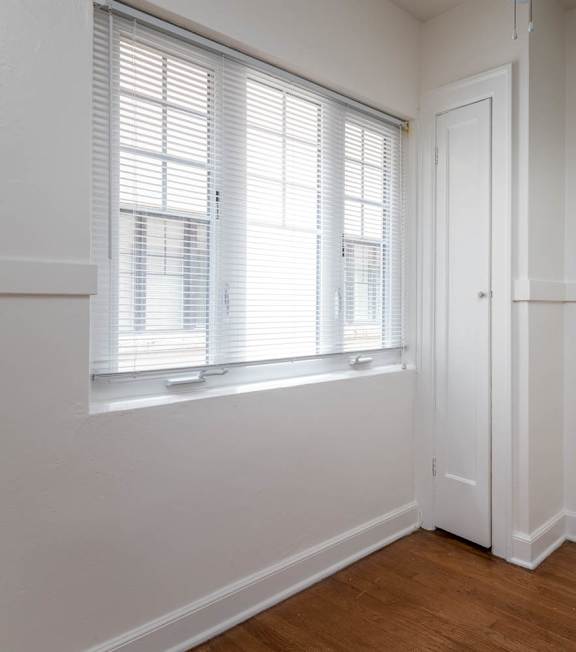 A room with a white door and a window with blinds.