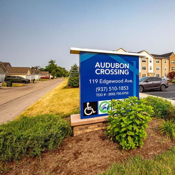 a sign in a parking lot with a building in the background