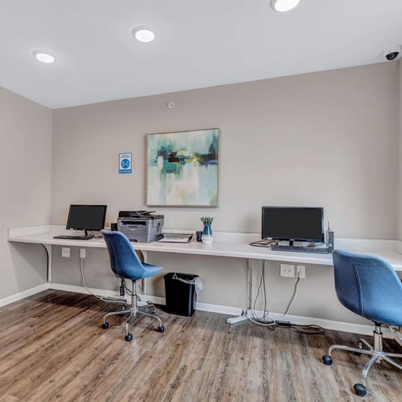 a home office with two computer desks and two blue chairs