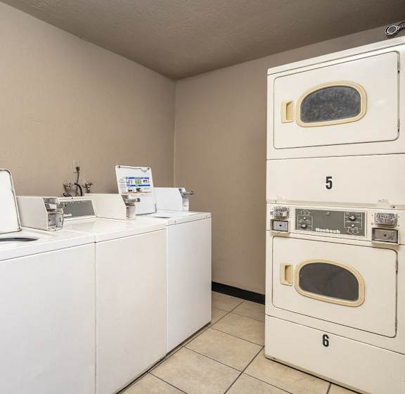 A laundry room with washing machines and dryers.