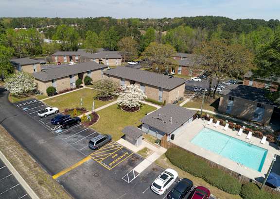 A parking lot with a pool and apartment buildings in the background.