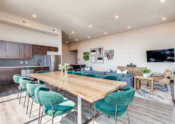A modern open-plan living and dining area with a wooden table and green chairs.