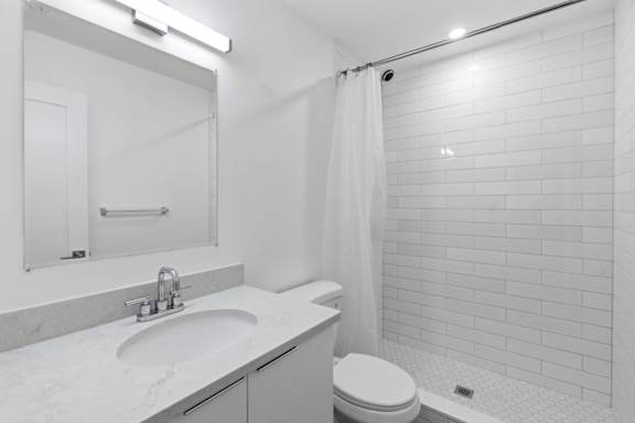 A white bathroom with a toilet, sink, and shower.