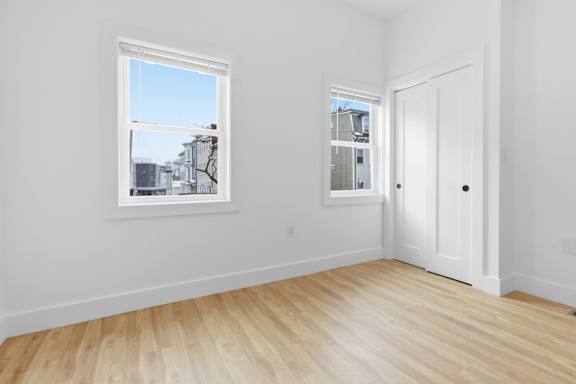 A room with a white door and a window with a view of the street.