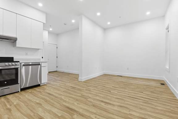 A kitchen with a stainless steel oven and wooden flooring.