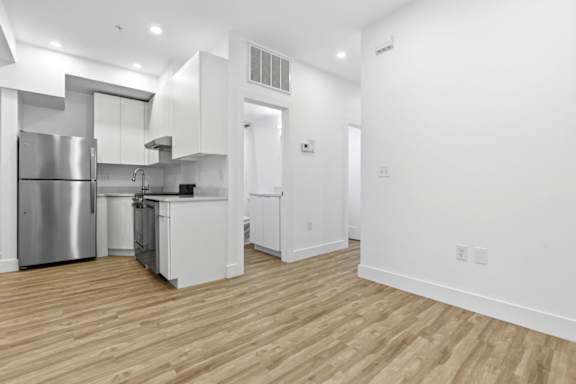 A modern kitchen with wooden floors and stainless steel appliances.