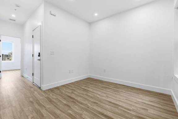 A room with wooden flooring and white walls.