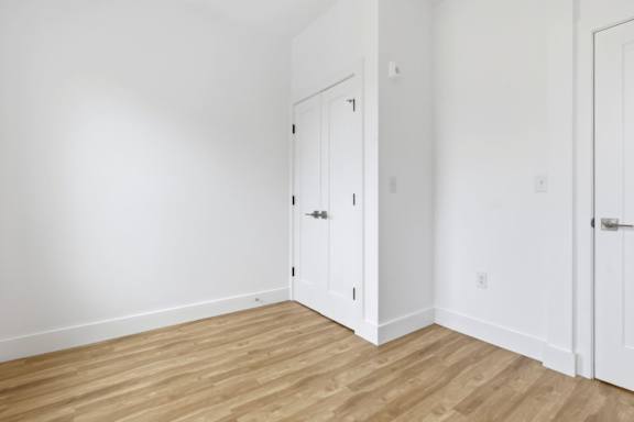 A white door is in a room with wooden floors.