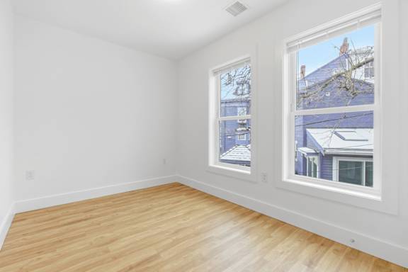 Empty room with a window showing a blue house outside.