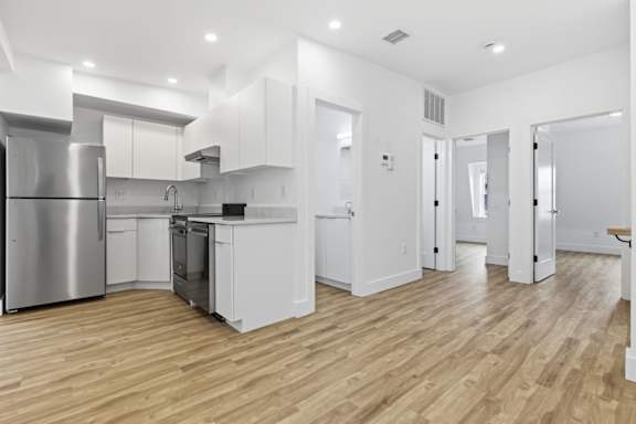 A modern kitchen with wooden floors and stainless steel appliances.