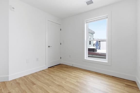 A room with a white door and a window showing a blue house outside.