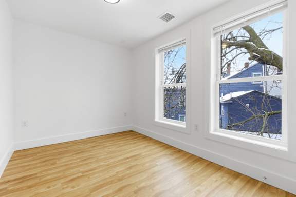 A room with a window and wooden flooring.