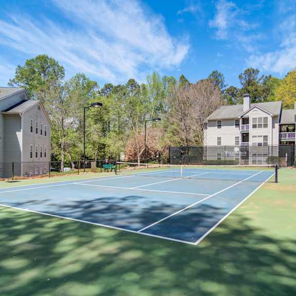Apartments in Marietta Georgia for Rent – Wood Pointe Apartments - A tennis court is surrounded by trees and houses.