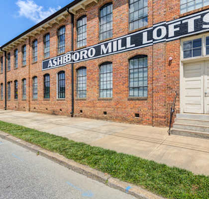 A brick building with a sign that says Ashboro Mill Lofts.