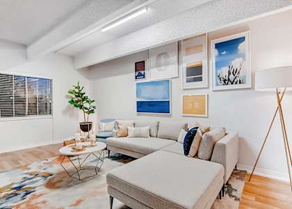 A living room with a grey couch, a small table, and a floor lamp.