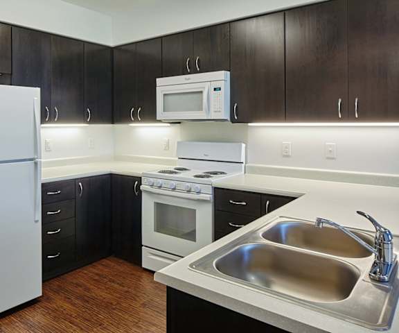 A kitchen with a white refrigerator, a stove, a microwave, and a sink.