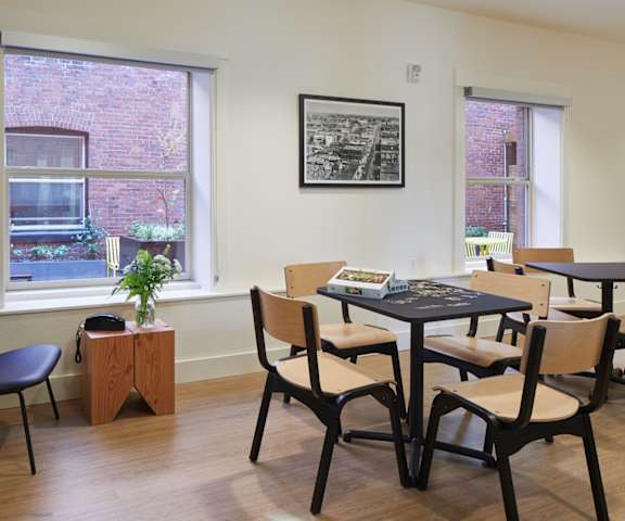 A black chair sits in front of a window in a room with a table and chairs.