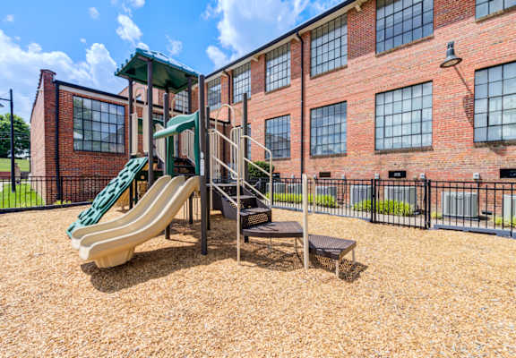 A playground with a green slide and a brown surface.