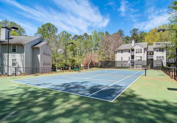 Apartments in Marietta Georgia for Rent – Wood Pointe Apartments - A tennis court is surrounded by trees and houses.