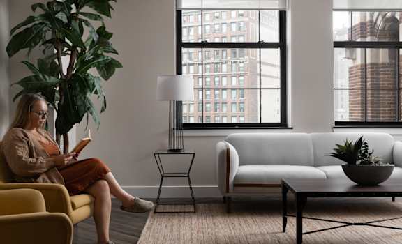 a woman sitting on a couch in a living room reading a book