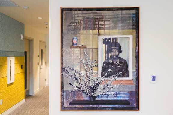 a painting on a wall in a hallway with a vase of flowers