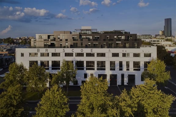 an aerial view of a white building with trees in front of it