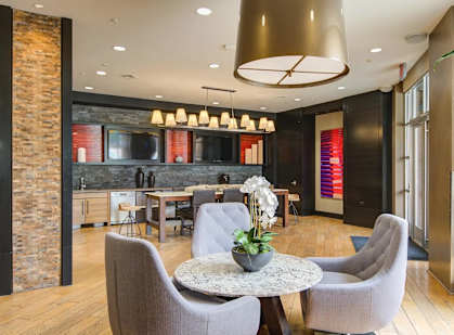 A modern dining room with a round table and grey chairs.
