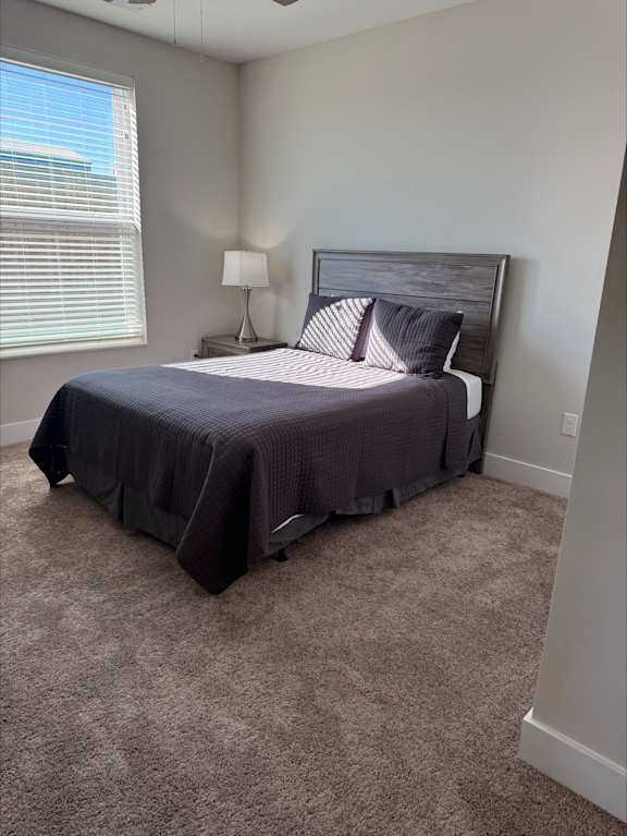 A bedroom with a bed, lamp, and carpet.