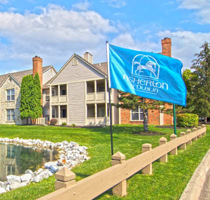 an image of an apartment building with a pond in front of it