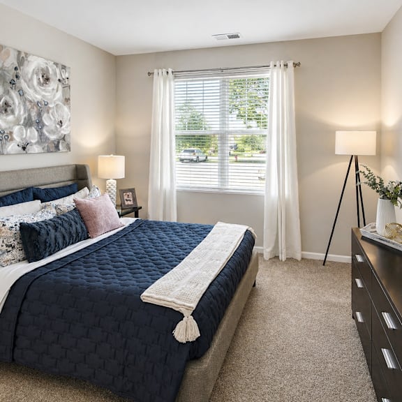 A bedroom with a large bed and a large floral painting on the wall.