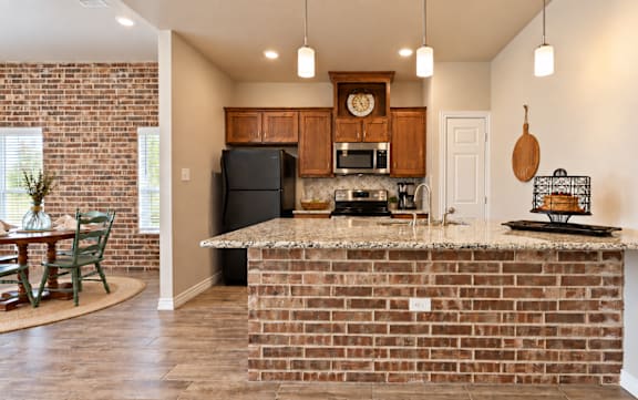 A kitchen with a brick wall and a wooden counter.