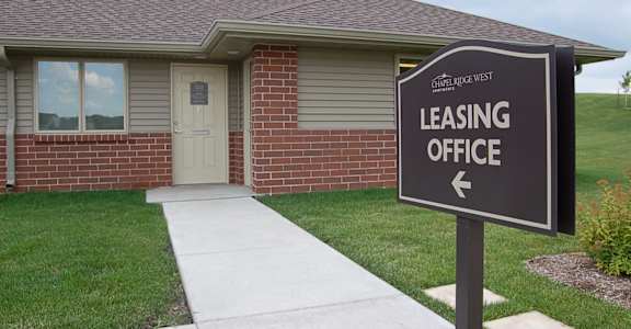 a house with a leasing office sign in front of it