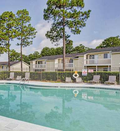 A swimming pool surrounded by trees and chairs.at Patriot Point Apartment Homes, Spring Lake