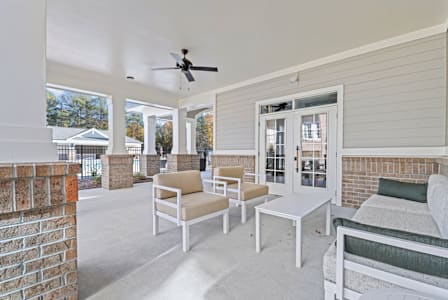 A living room with a wooden table and white couches. at Litchford 315 Apartments, Raleigh, NC, 27615