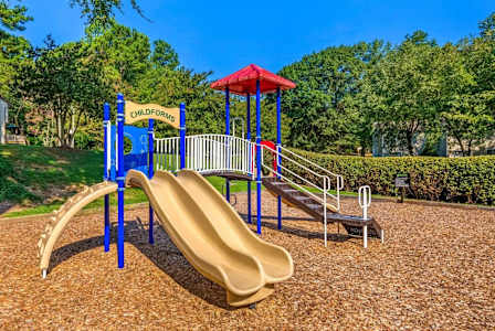 A playground with a yellow slide and a red roofed structure.