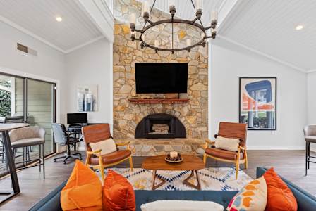 A living room with a stone fireplace and a chandelier.