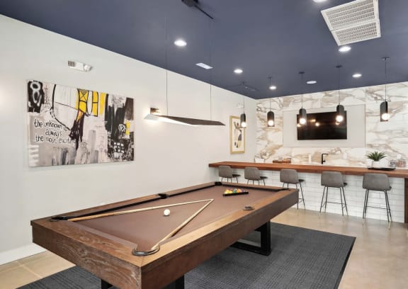 a pool table in a clubhouse with a bar and a television