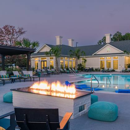 a swimming pool with a fire pit and lounge chairs