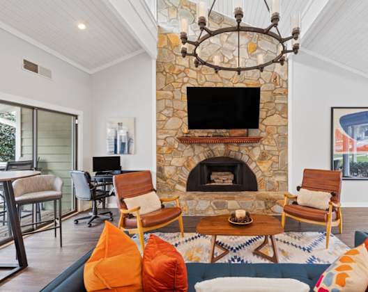 A living room with a stone fireplace and a chandelier.