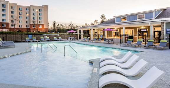 a swimming pool with chairs and a building in the background