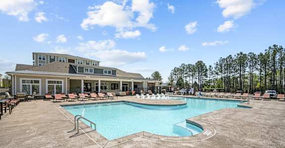 a resort style pool with lounge chairs and a building in the background